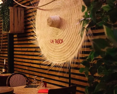 Grand chapeau de paille brodé « La Tasca » au mur du restaurant